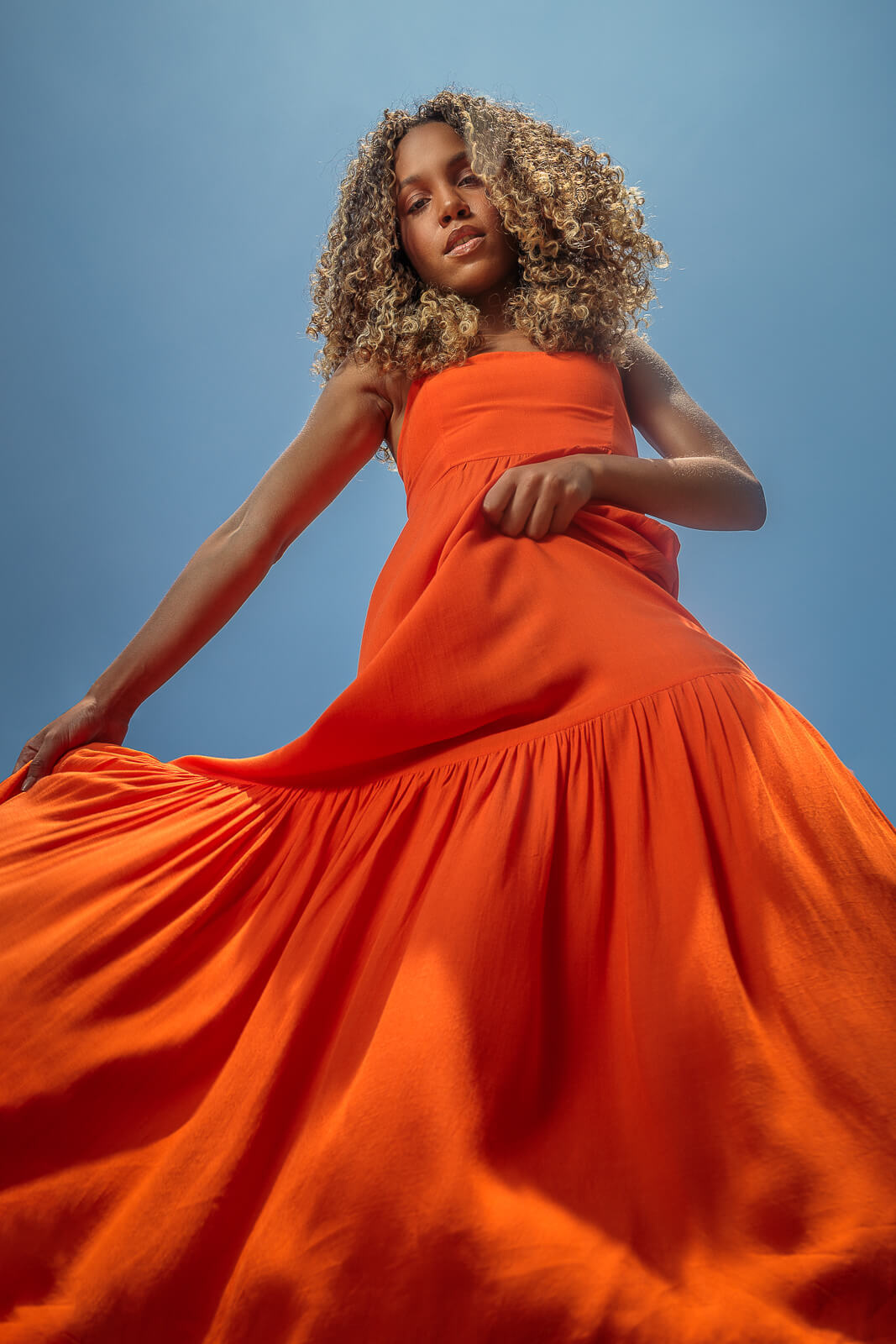 modelo linda posando com vestido laranja em céu azul para fotógrafo de moda paulo henrique lima no studio em home de piratininga niterói