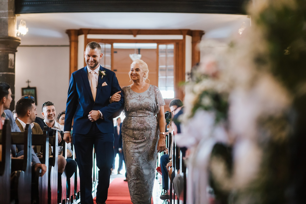noivo a entrar na igreja com a mãe no casamento em são miguel 